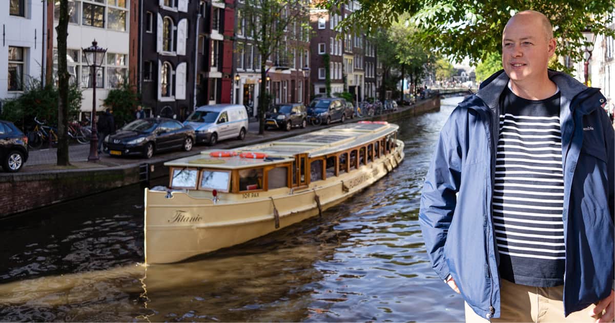 Gerrit devant un petit bateau de canal à Amsterdam.