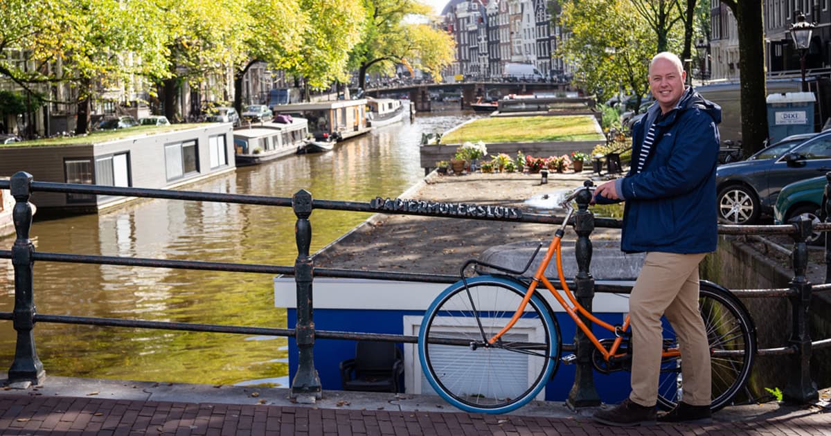 Gerrit se tient au bord des canaux d'Amsterdam à côté d'un vélo classique.
