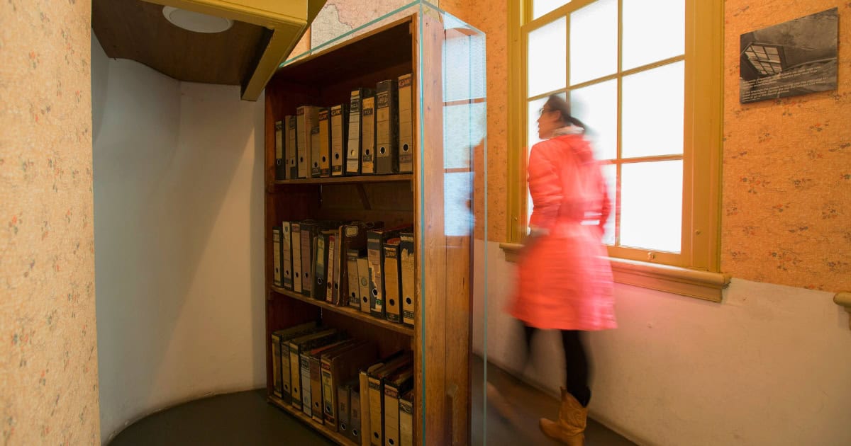 La porte cachée derrière la bibliothèque dans la Maison d'Anne Frank avec un visiteur qui passe.